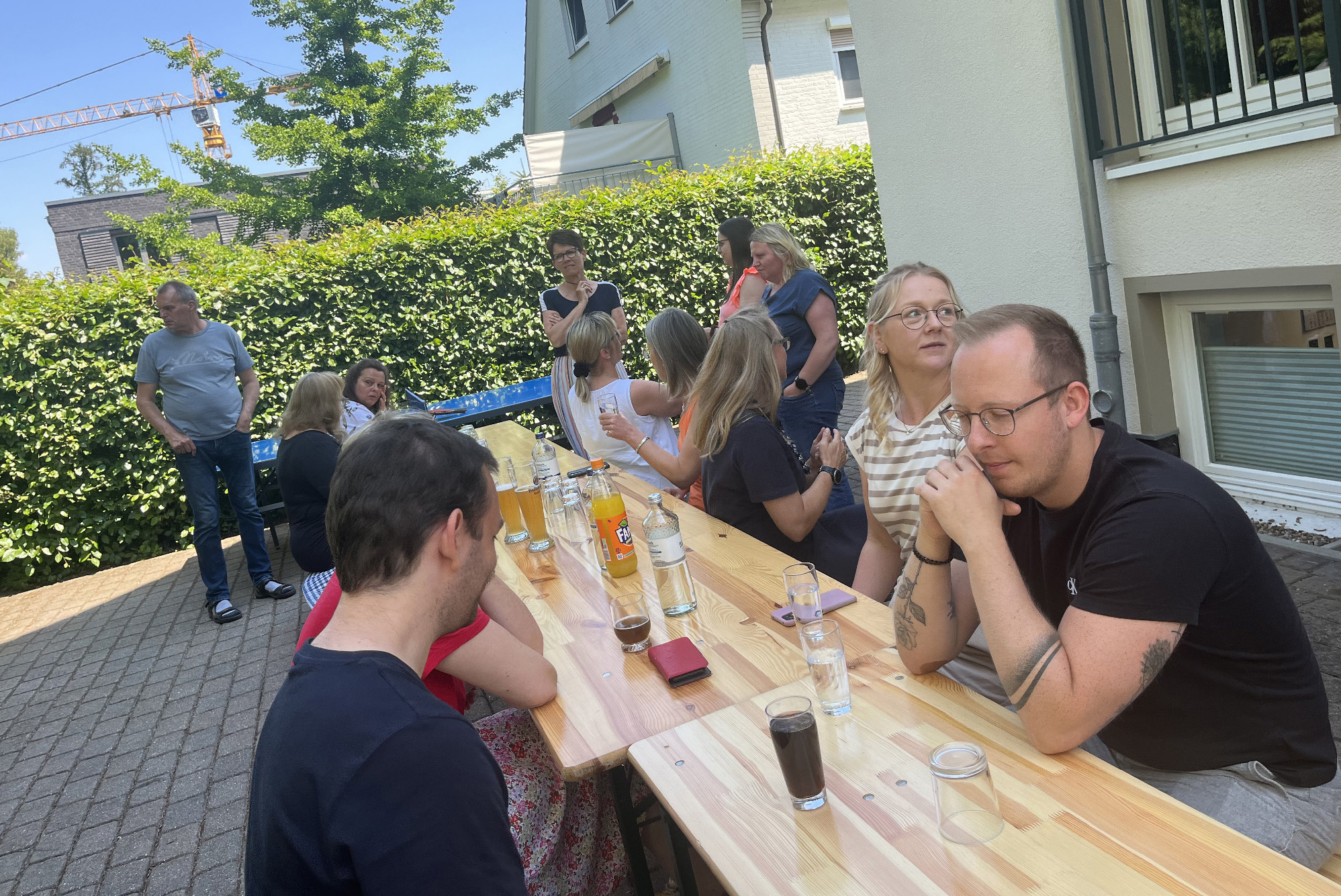 Mehrere Personen sitzen gemeinsam an einer Bierbank bei schönem Wetter.